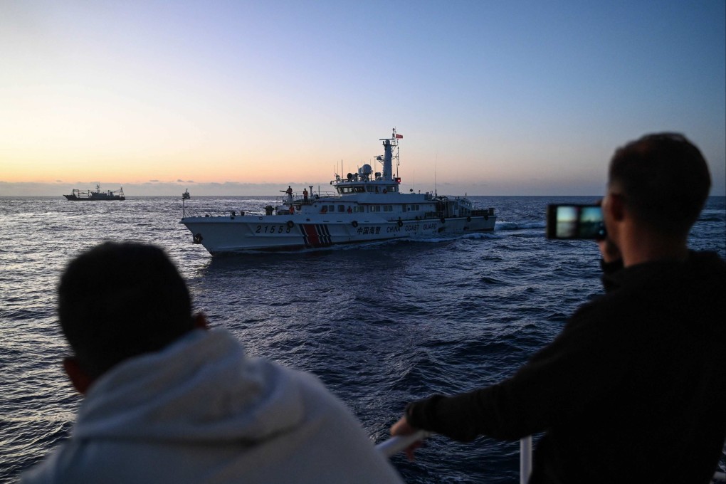 Philippine Coast Guard personnel filming a China Coast Guard vessel during a supply mission in disputed waters of the South China Sea. Photo: AFP