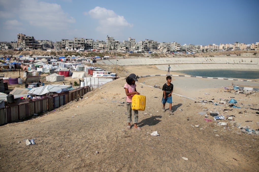 Palestinian children walk near a wastewater pool as displaced Palestinians shelter in a tent camp in Khan Younis in southern Gaza on Sunday. Photo: Reuters