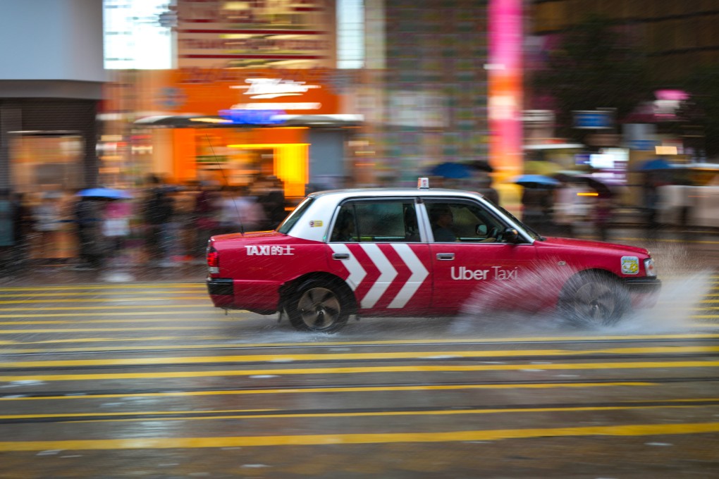 A taxi with the an ad for Uber splashes through water on the street during a rainstorm in Causeway Bay on May 21. While some taxi drivers have signed up for the ride-hailing platform, a large number are opposed to it operating in Hong Kong. Photo: Sam Tsang