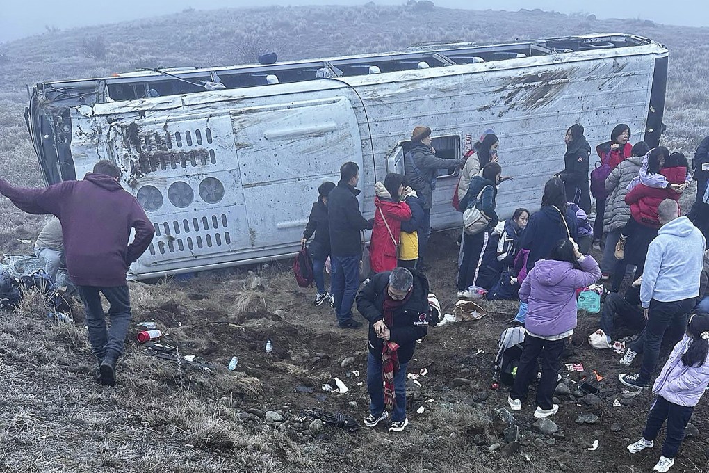 Passengers are seen beside one of the tour buses that overturned on a stretch of road near Lake Tekapo, New Zealand. Photo: Grace Duggin/via AP