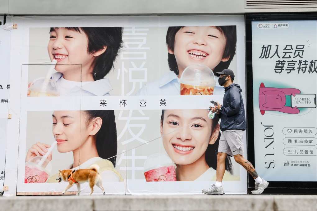 A man walks his pet dog in front of advertisement placards near a shopping mall in Beijing. Photo: EPA-EFE