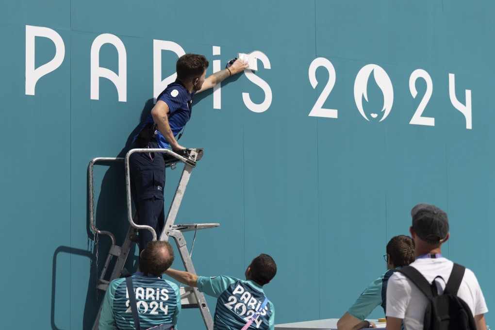 A volunteer fixes a sign in the Olympic Village in Paris. Photo: AP