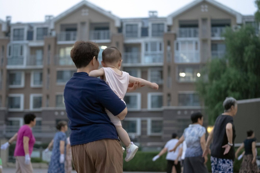 A woman carries a child at a park in Beijing. China’s population shrank by 2 million people last year, a trend that looks set to continue. Photo: Bloomberg