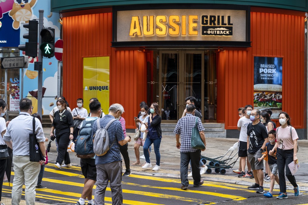 Pedestrians cross the street in front of the Australian-themed American casual dining restaurant chain by Outback Steakhouse, Aussie Grill, in Hong Kong. Photo: Getty Images