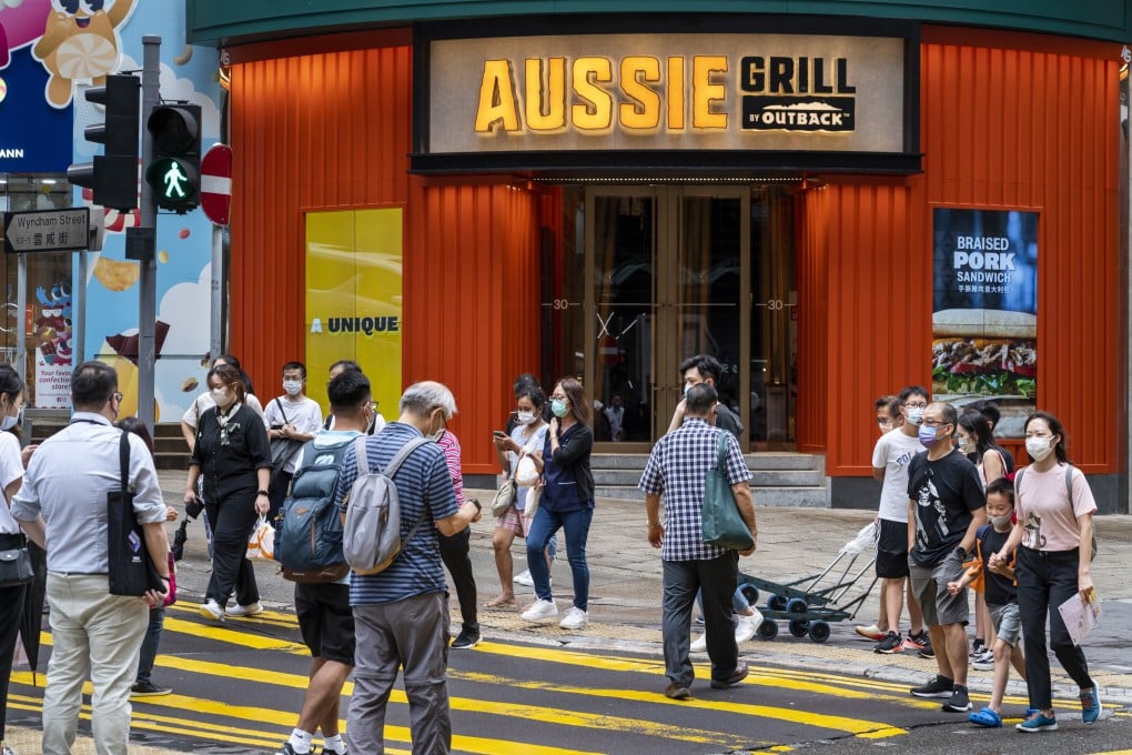 Pedestrians cross the street in front of the Australian-themed American casual dining restaurant chain by Outback Steakhouse, Aussie Grill, in Hong Kong. Photo: Getty Images