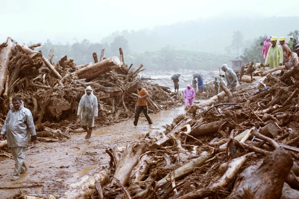 People walk past debris at a landslide site after multiple landslides in the southern state of Kerala, India on Tuesday. Photo: Reuters
