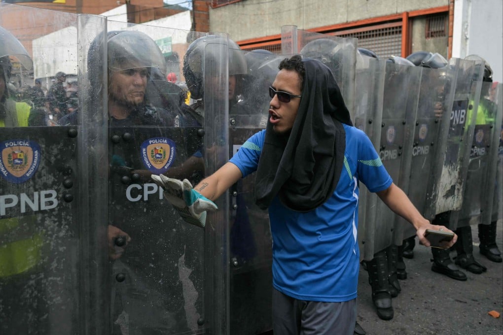 A demonstrator walks in front of police officers during a protest against Venezuelan President Nicolas Maduro’s government in Caracas. Photo: AFP