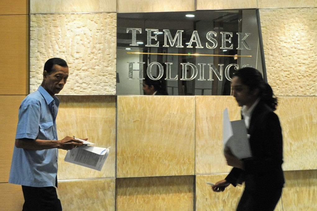 Office workers walk past Singapore state-linked investment firm Temasek Holdings sign in Singapore. Photo: AFP