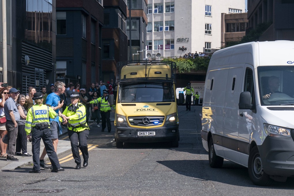 A man is held back by police as a prison van carrying stabbing suspect Axel Rudakubana leaves Liverpool Crown Court, in Liverpool, UK on Thursday. Photo: PA via AP