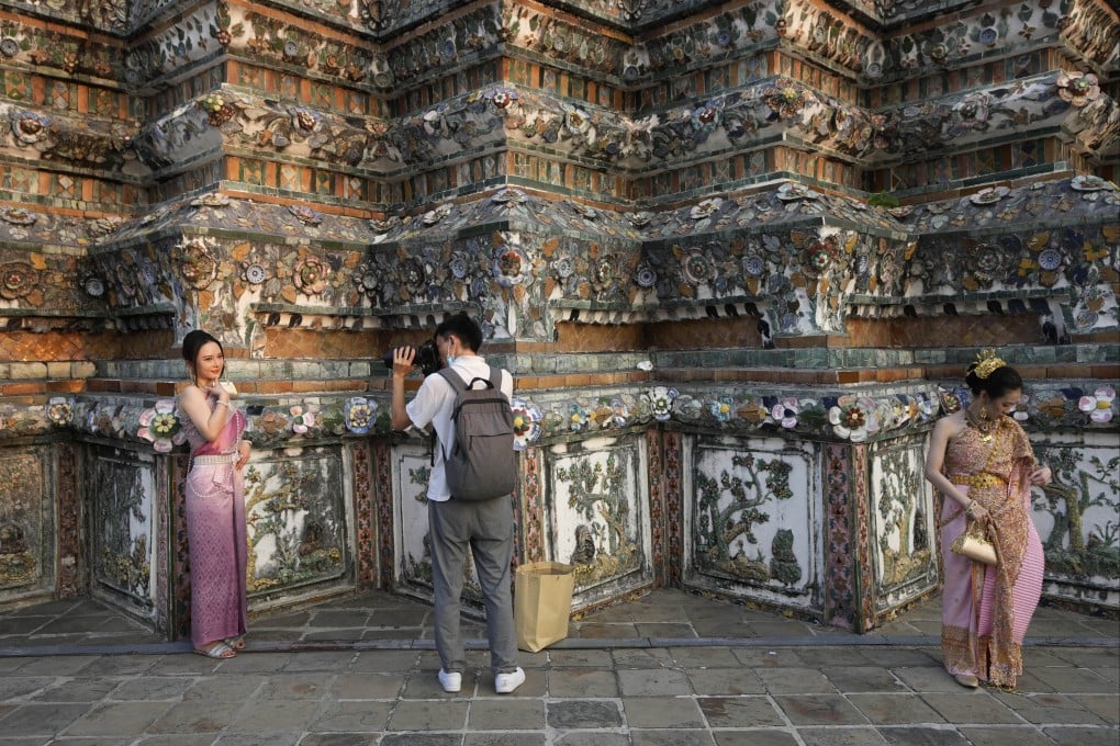 A Chinese tourist in traditional Thai dress poses for a photo at Wat Arun or the Temple of Dawn in Bangkok in 2023. Photo: AP