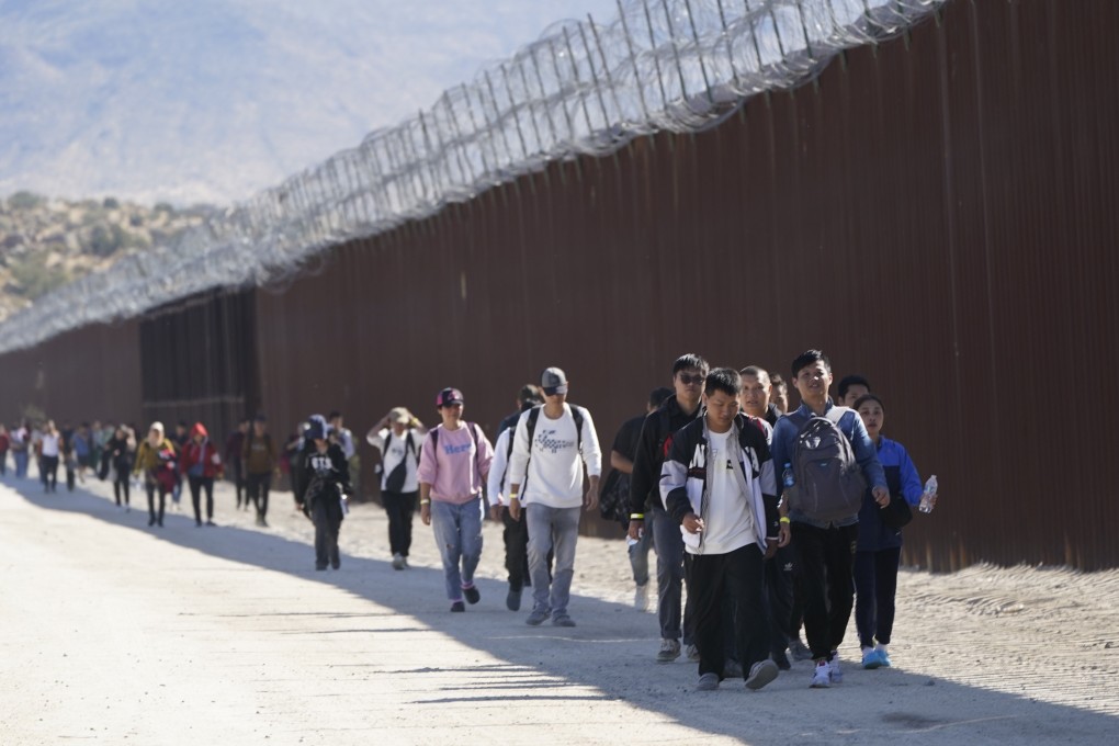 A group of people, including many from China, walk along the wall after crossing the border with Mexico to seek asylum, near Jacumba, California. File photo: AP