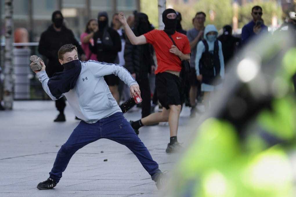 A demonstrator throws a brick during a protest in Liverpool, England, on Saturday. Photo: PA via AP
