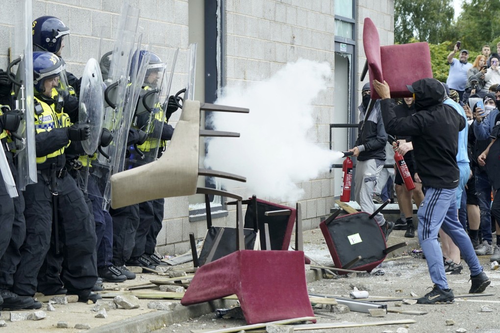 A rioter throws a chair at police officers during an anti-immigration protest outside the Holiday Inn Express in Rotherham, England, on August 4. Photo: AP