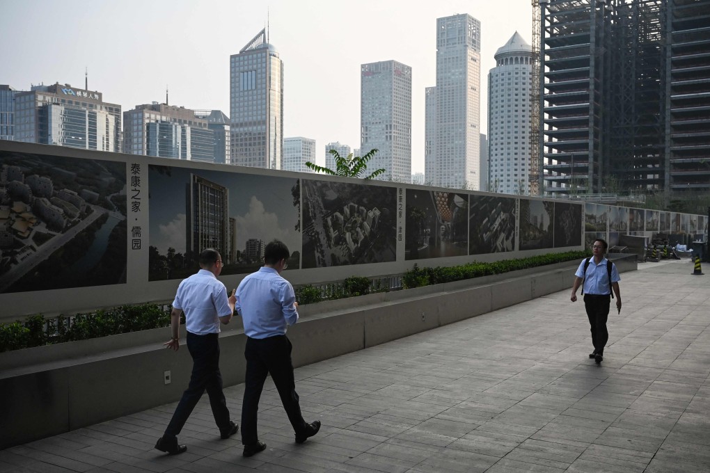 Office workers walk beside a construction site in the central business district of Beijing on July 11, 2024. Photo: AFP