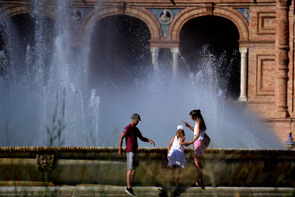 People try to cool themselves off at the fountain at the Plaza de España in Seville on July 23. Photo: AFP