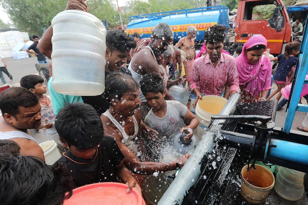 People rush to fill water canisters at a Delhi Jal Board tanker in a makeshift settlement in Geeta Colony, New Delhi, on June 26. Photo: EPA-EFE
