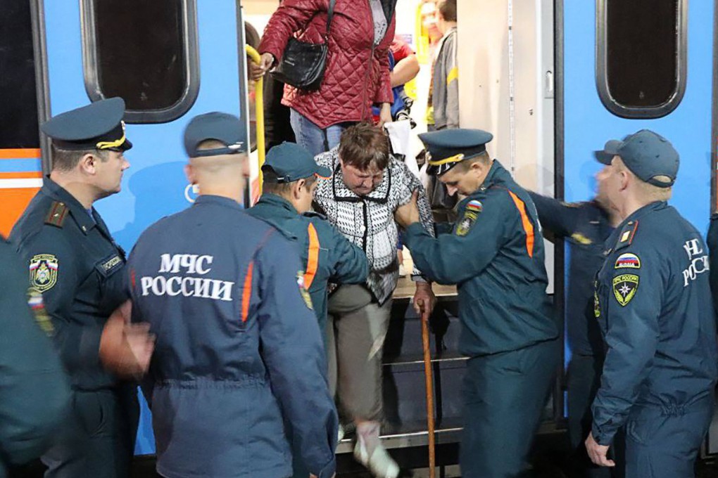 Russian Emergency Situations Ministry personnel help evacuees from the Kursk region, as they arrive at a railway station in Oryol on Friday. Photo: Russian Emergency Situations Ministry via AFP