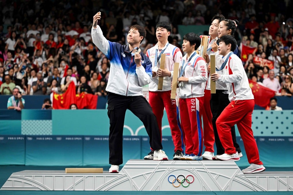 Medallists from South Korea, North Korea and China gather on the podium for a selfie at the end of their mixed table tennis doubles competition at the Summer Olympic Games at the South Paris Arena in Paris on July 30. Photo: AFP