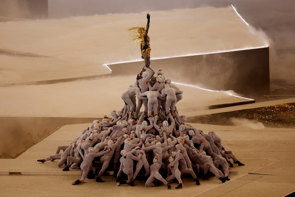 The Golden Voyager stands atop a pile of masked dancers in a performance during the closing ceremony. Photo: Reuters