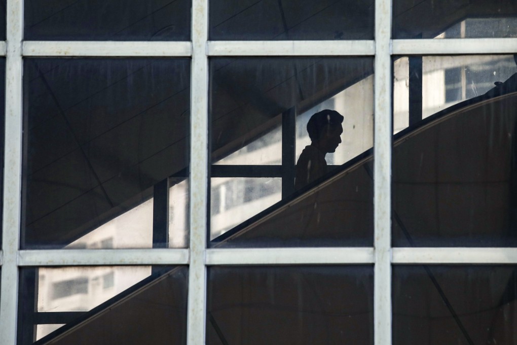 A person riding an escalator is reflected in the glass of an office building in Admiralty on October 17, 2023. Photo: Xiaomei Chen