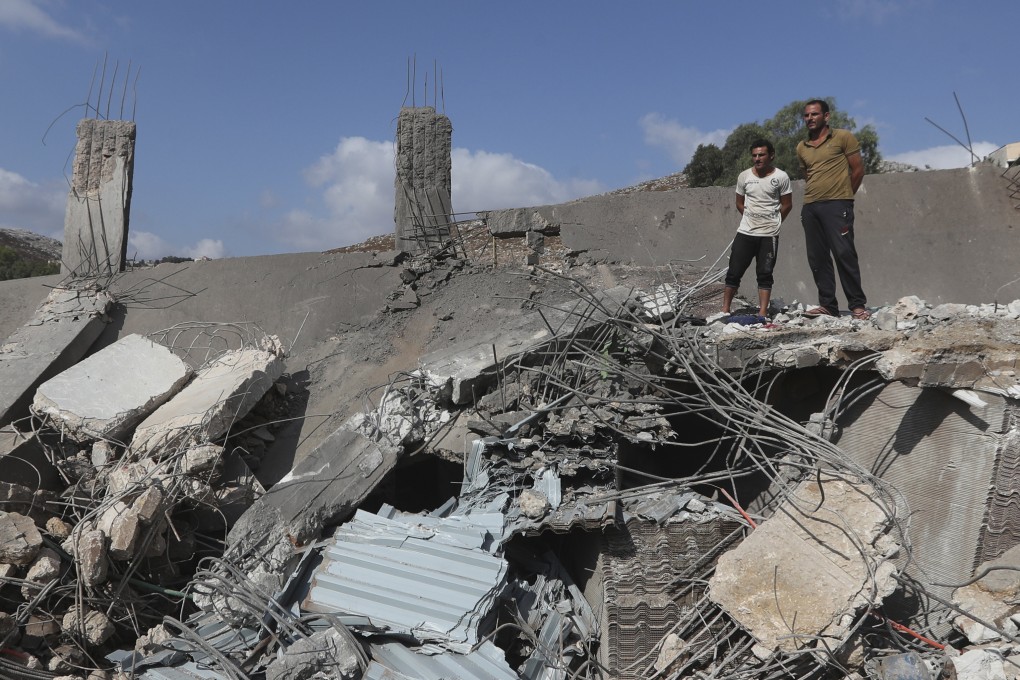 Civilians watch an industrial area destroyed by an Israeli airstrike, in south Lebanon on Saturday. Photo: AP