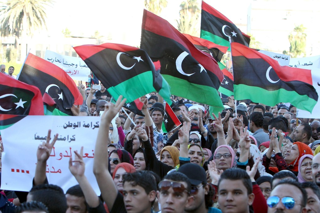 Libyan protesters hold placards and the national flag during a demonstration in Tripoli, in May, 2014. Photo: EPA
