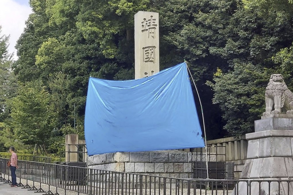 A blue sheet covers a stone pillar on which graffiti was found at Yasukuni Shrine in Tokyo on Monday. Photo: AP
