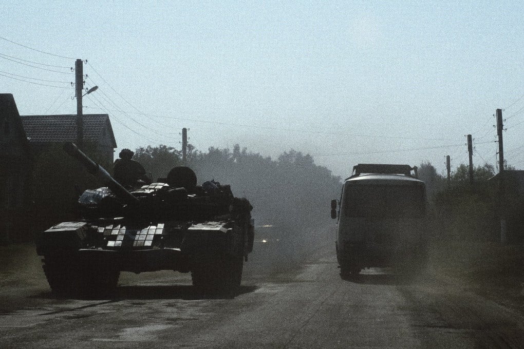A civilian bus rides past a Ukrainian tank on a road in a village near the border with Russia in the Sumy region, Ukraine, on August 18. Photo: EPA-EFE