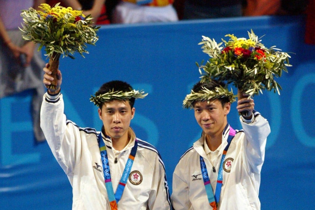 Silver medalists Ko Lai-chak and Li Ching of Hong Kong wave from the podium after the medal ceremony for the men’s doubles table tennis at the Athens Olympic Games on August 21, 2004. Photo: Reuters