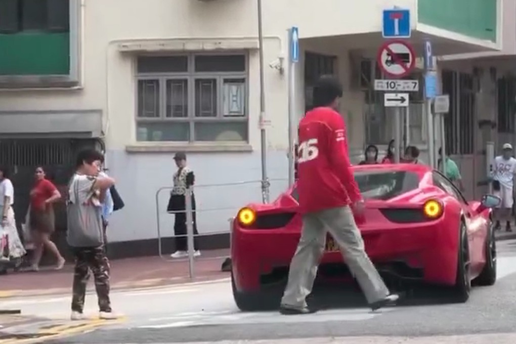 A screengrab shows singer Denis Kwok returning to his Ferrari after speaking to a pedestrian.who checks her elbow.
Photo: SCMP