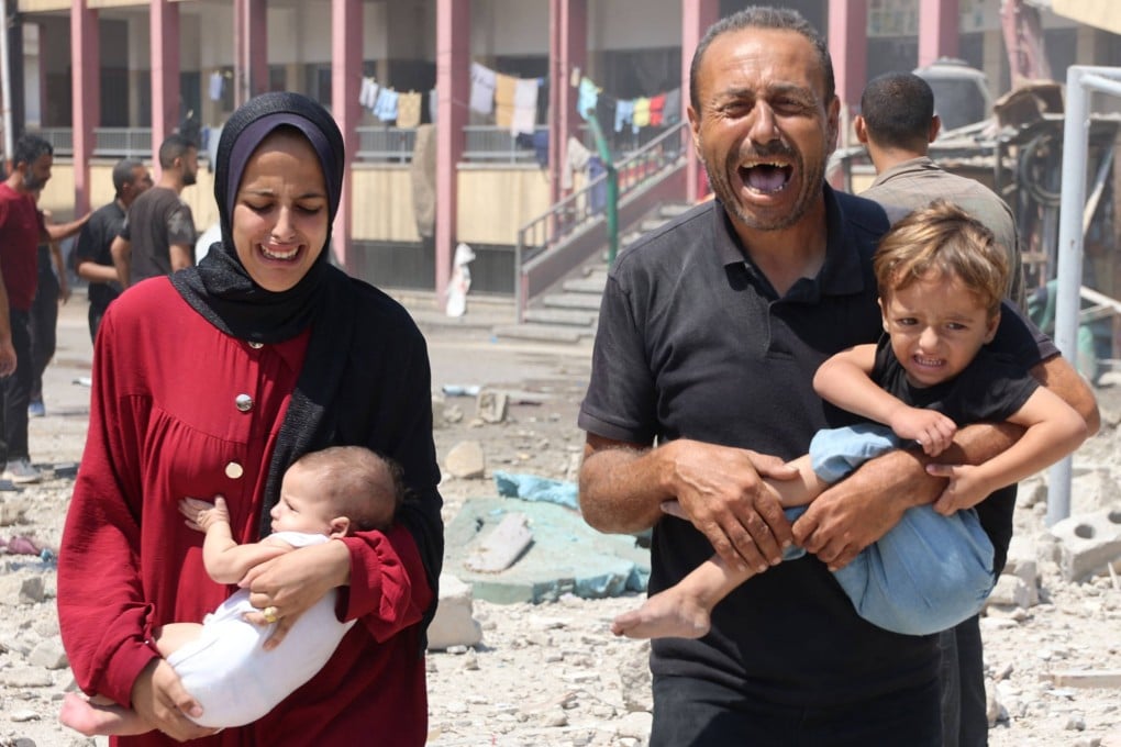 Palestinians carry their children as they flee after an Israeli strike on a school, housing displaced Palestinians, in central Gaza City on August 20. Photo: AFP