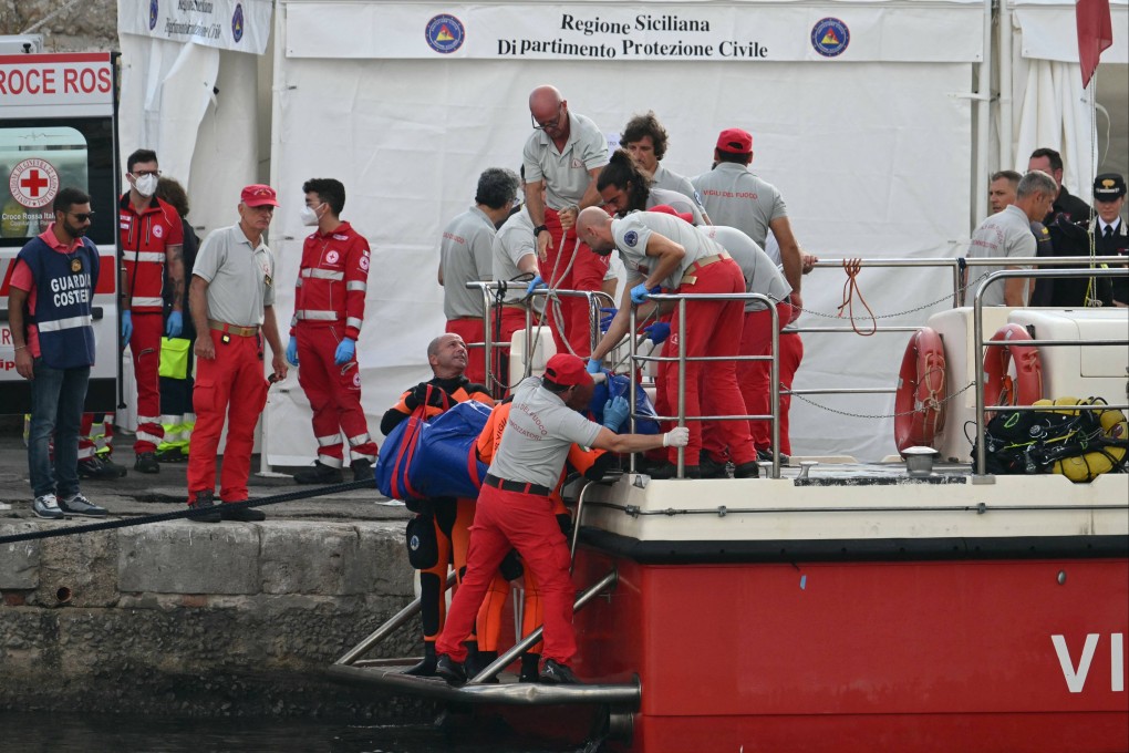 Rescuers carry a body after divers return in Porticello harbour. Photo: AFP