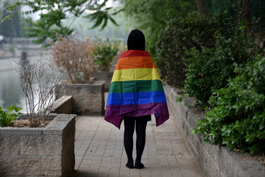 A student poses with a rainbow flag in Beijing. LGBTQ families have no law to cite when faced with situations like custody or divorce, as same-sex marriage is not recognised in China. Photo: AFP