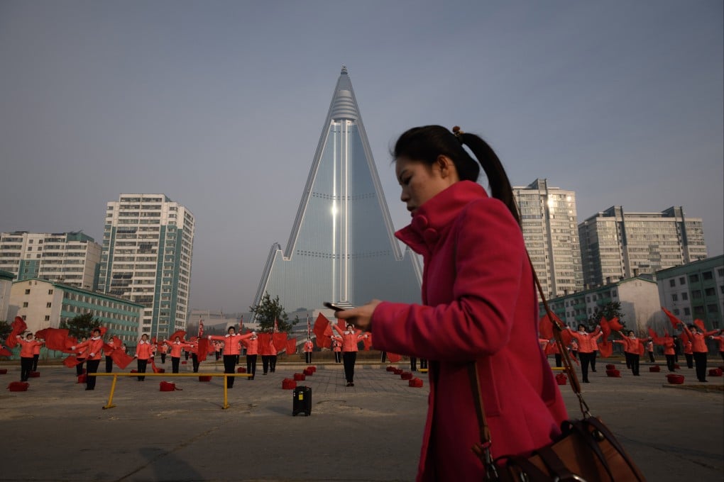 A woman walks past members of a Socialist Women’s Union propaganda troupe performing a dance and music routine in front of the Ryugyong hotel in Pyongyang. The Japanese government recognises 17 nationals as having been abducted in the 1970s and 1980s, although Pyongyang has only admitted to abducting 13 people. Photo: AFP