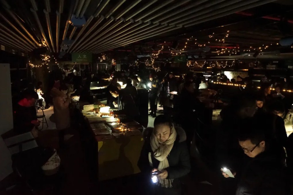 Fans of Shanghai Jifeng Bookstore’s last branch browse under mobile phone torches after the power supply is cut off pending lease expiry, in January 2018. Photo: WeChat/ 季风微读圈