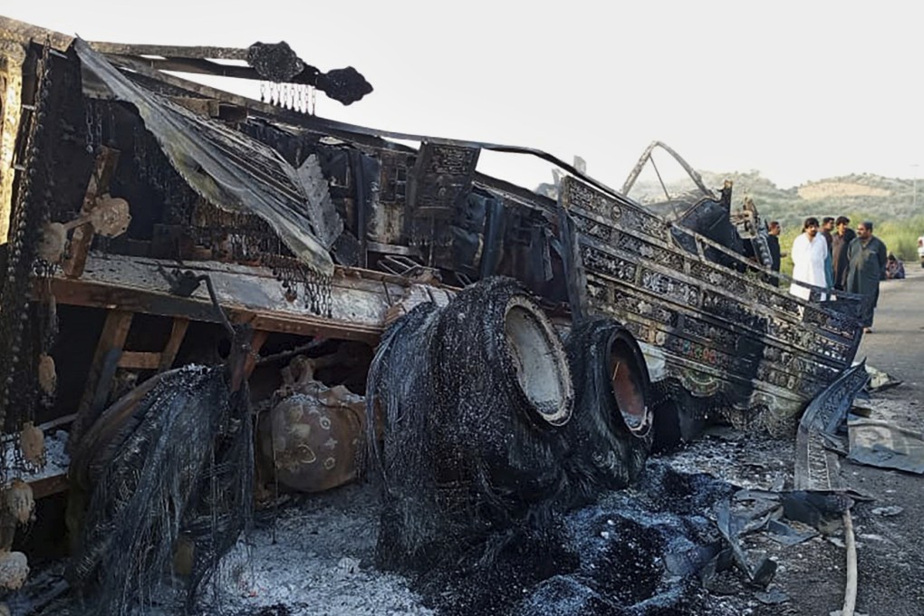 People look at a burnt vehicle which was torched by gunmen after they killed passengers at a highway in Balochistan province in Pakistan on Monday. Photo AP