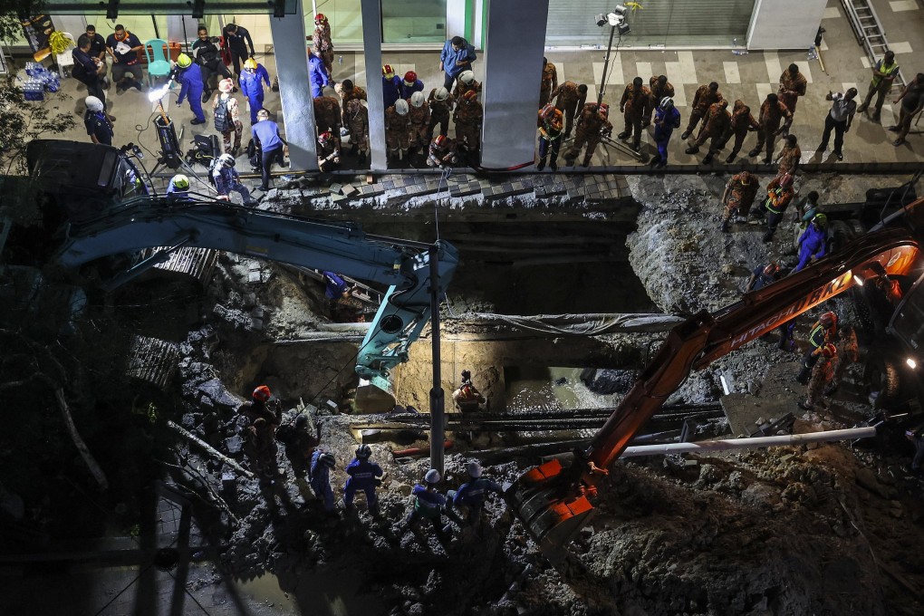 Rescuers inspect the site where a woman fell into the sinkhole in Kuala Lumpur on Friday. Photo: EPA-EFE