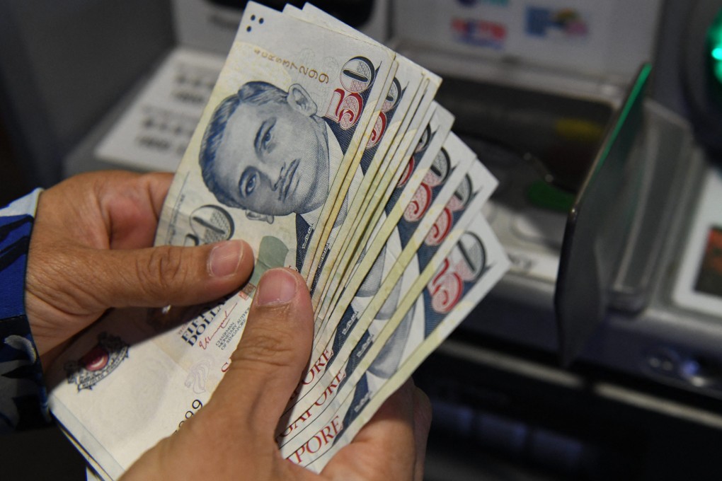 A customer withdraws Singapore dollar banknotes from an ATM. The city state’s currency is the second-best performer in Asia this year behind Malaysia’s ringgit. Photo: AFP