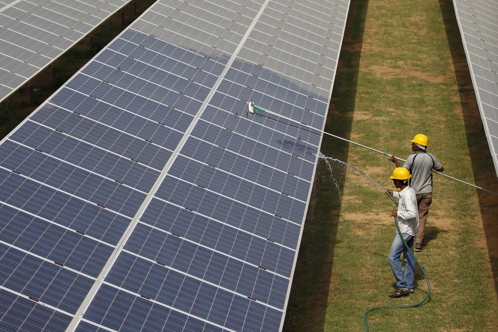 Workers clean photovoltaic panels inside a solar power plant in Gujarat, India. Photo: Reuters