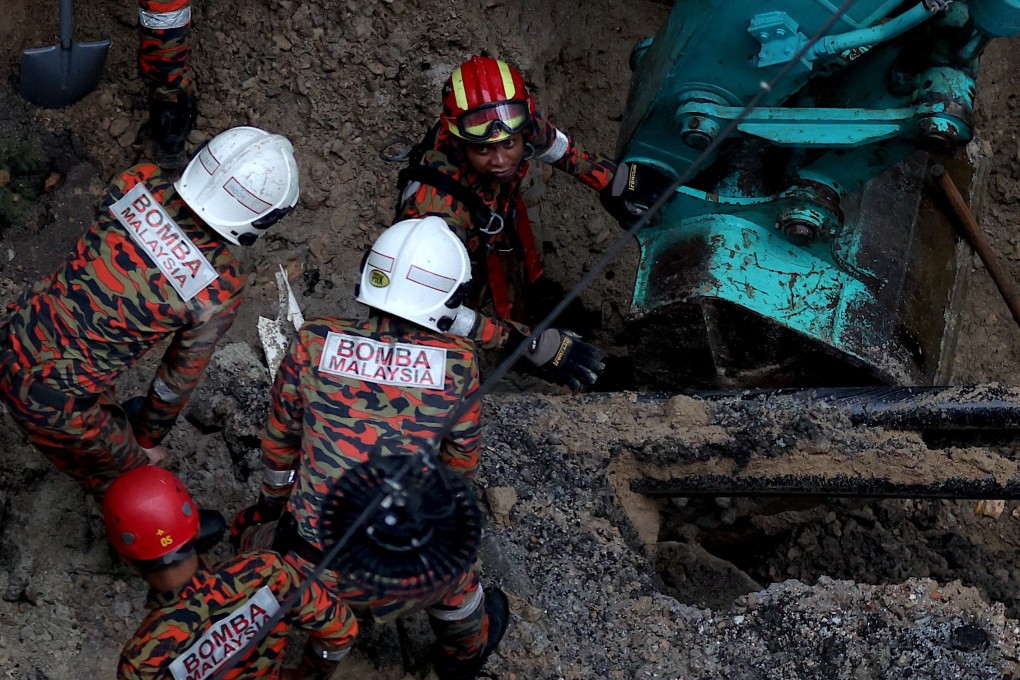Malaysian rescuers inspect the site where a woman fell into an eight-meter deep sinkhole in Kuala Lumpur on Friday. Photo: EPA-EFE