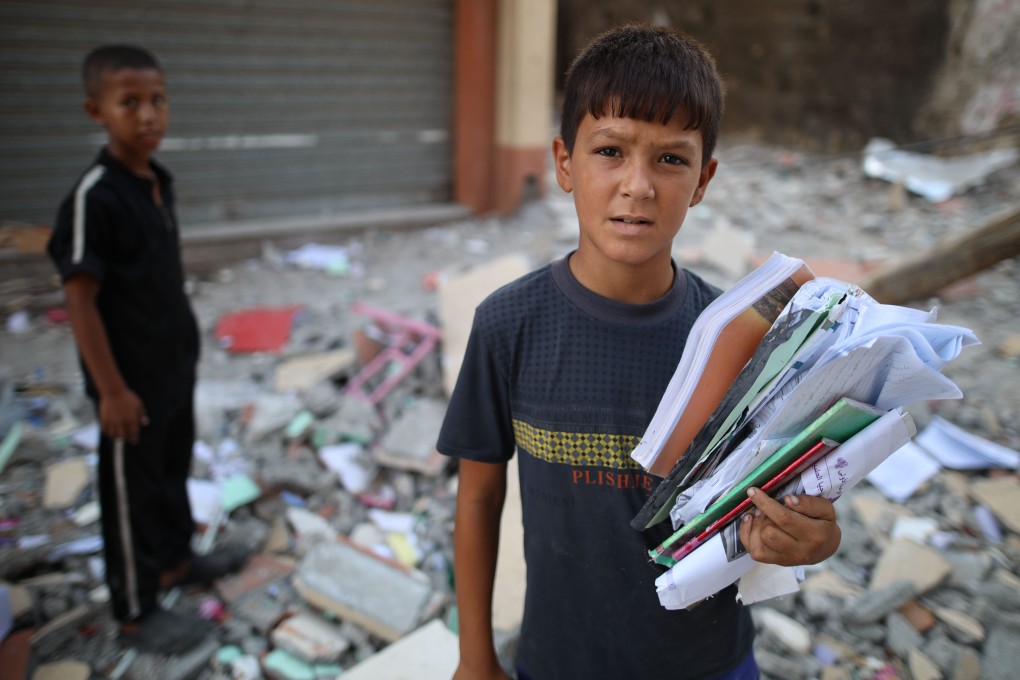 Palestinian children collect belongings from a building targeted in an Israeli airstrike in central Gaza’s Maghazi refugee camp on Tuesday. Photo: Xinhua