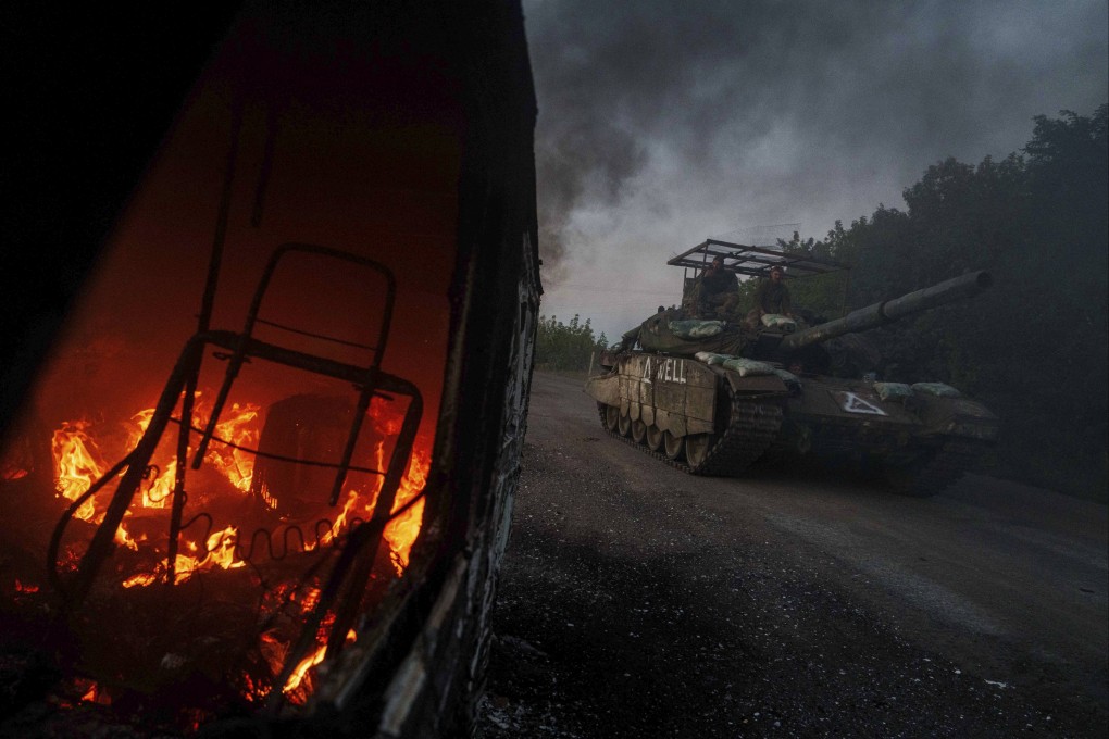 A Ukrainian tank passes by a burning car near the Russian-Ukrainian border, Sumy region, Ukraine. Photo: AP