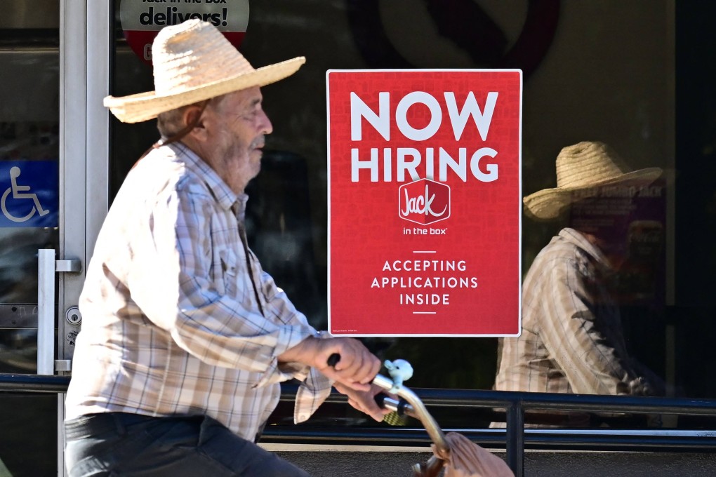 A cyclist rides past a “Now Hiring” sign posted on a business storefront in San Gabriel, California, on August 21. US figures for the 12 months ending in March showed there were 818,000 fewer jobs than previously reported in the largest downward revision since 2009. Photo: AFP