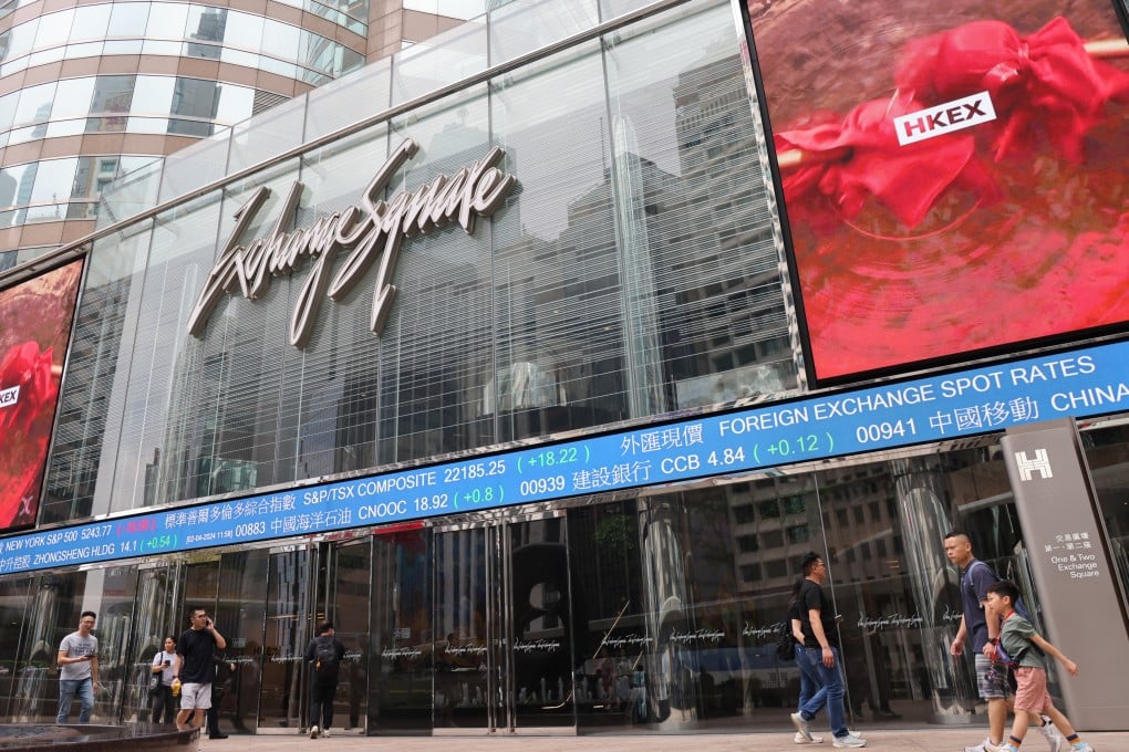 People walking past electronic boards outside the Exchange Square in Central in April 2024. Photo: Jelly Tse.