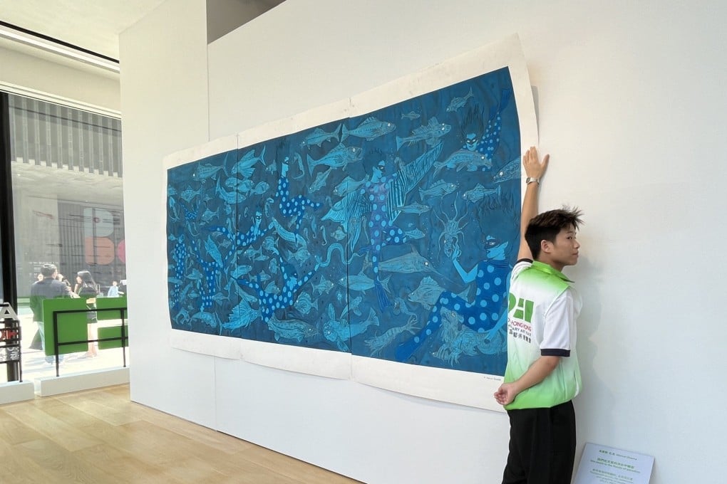 A member of staff holds up Marcel Dzama’s “We Swam in the Floods of Paradise” after it was partially blown off the wall at the inaugural Art021 Hong Kong Contemporary Art Fair, on August 29, 2024. The fair was granted HK$15 million by the Mega Arts and Cultural Events Fund. Photo: Enid Tsui