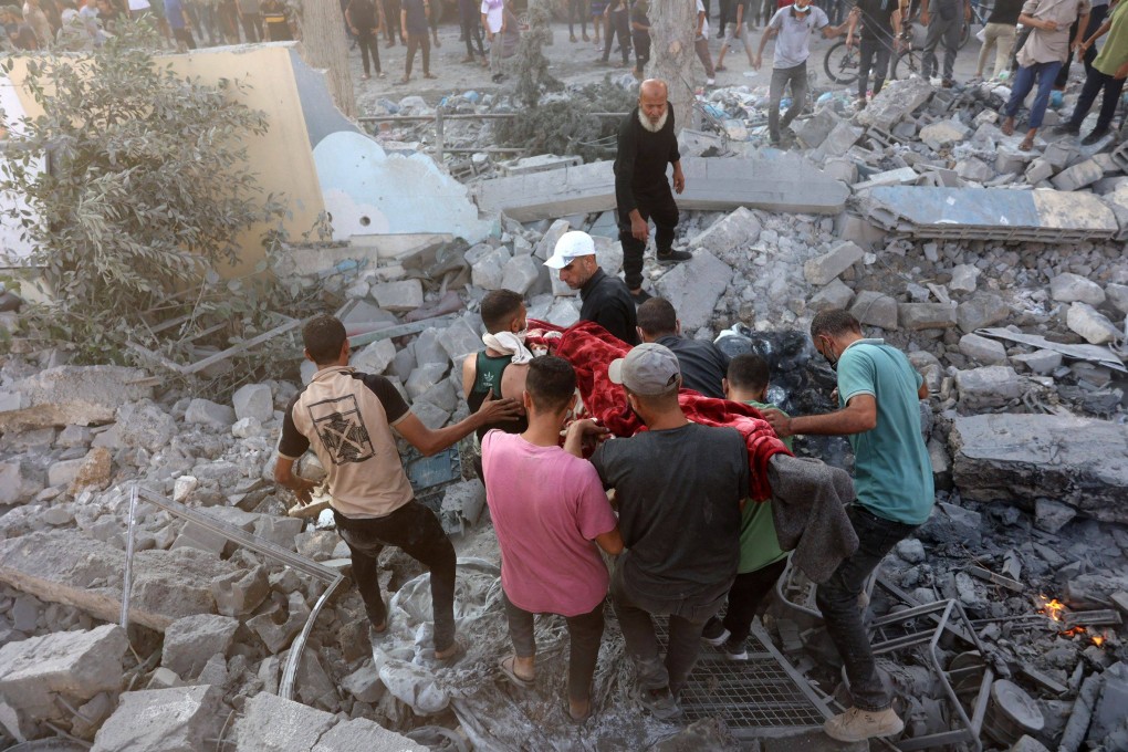 People carry the body of a victim recovered from the rubble following an Israeli strike which reportedly targeted a school in the Zeitoun district on the outskirts of Gaza City on Sunday. Photo: AFP