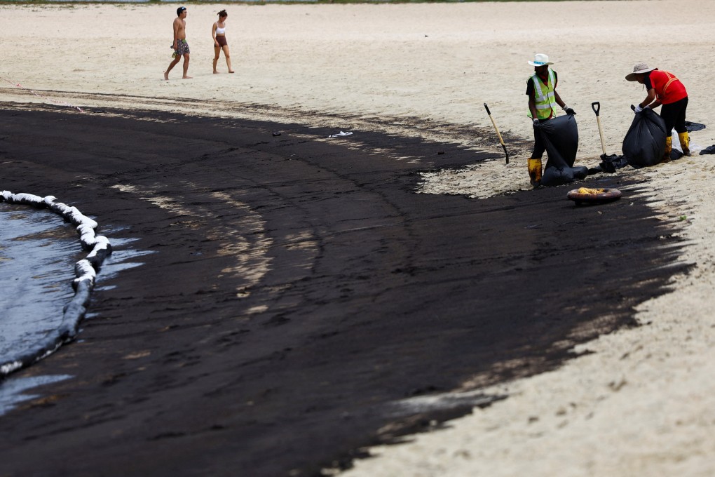 Workers clean up the beach following an oil slick, at Tanjong Beach in Sentosa, Singapore on June 15. Photo: Reuters