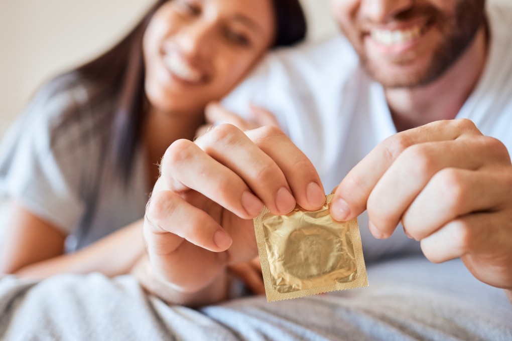 A man holding a condom with his partner by his side. Photo: Shutterstock