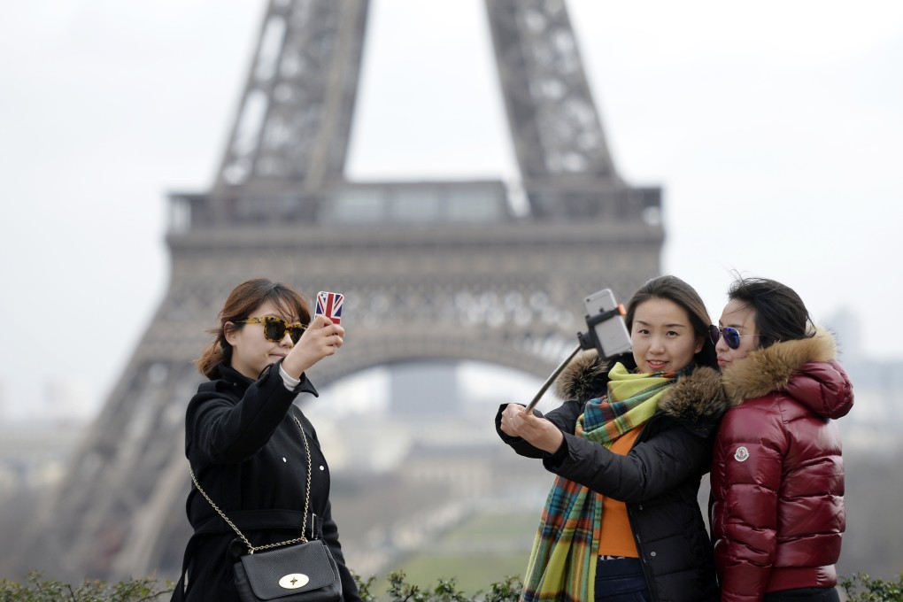 Tourists taking selfies in front of the Eiffel Tower in Paris. Photo: AFP