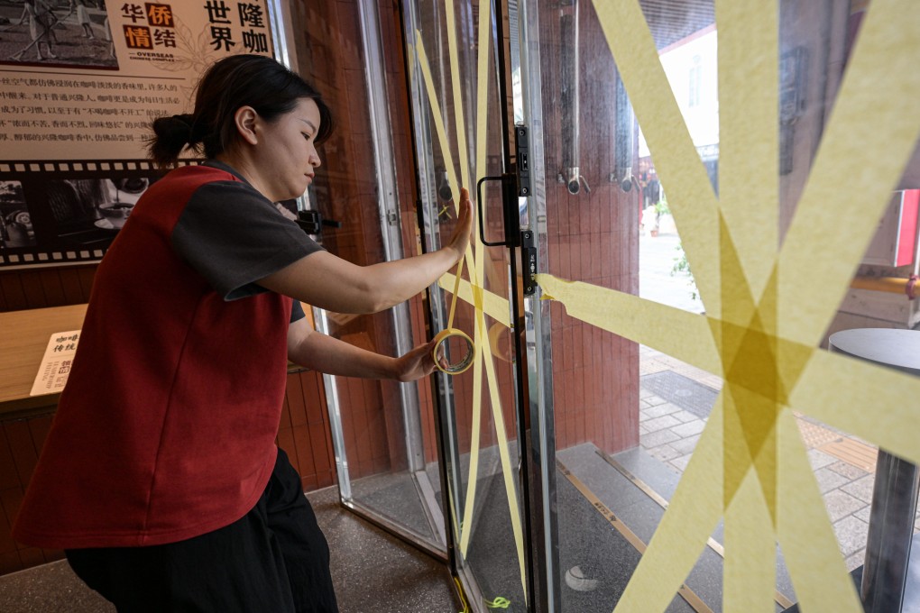 A cafe worker reinforces a glass window in Haikou on Thursday in preparation for Super Typhoon Yagi. Photo: Xinhua